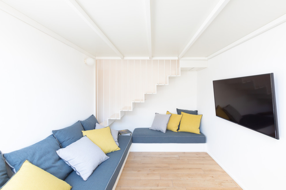 Modelo de cine en casa cerrado actual pequeño con paredes blancas, suelo de madera en tonos medios, televisor colgado en la pared y suelo beige
