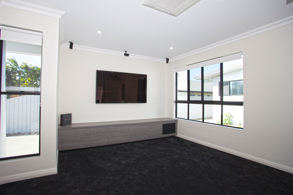 Modelo de cine en casa cerrado minimalista de tamaño medio con paredes blancas, moqueta, televisor colgado en la pared y suelo gris