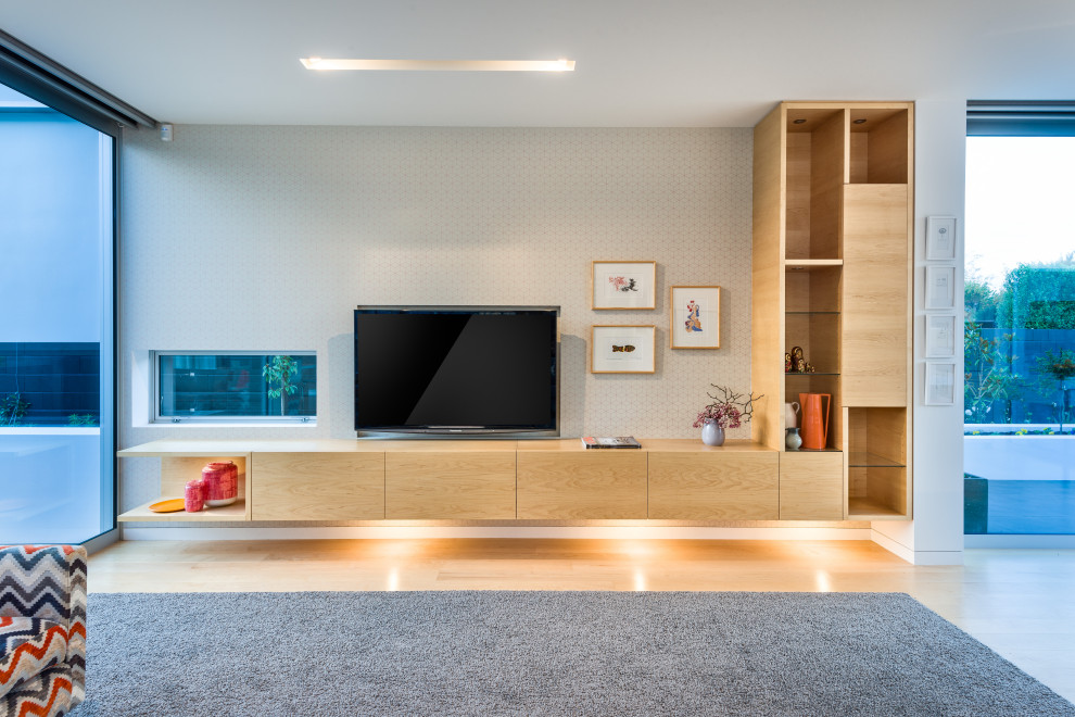 Idéer för ett stort modernt öppen hemmabio, med vita väggar, ljust trägolv, en väggmonterad TV och beiget golv