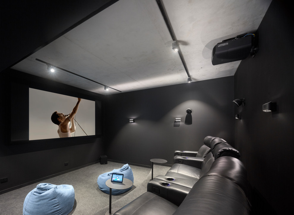 Diseño de cine en casa cerrado contemporáneo con paredes negras, moqueta, pantalla de proyección y suelo gris
