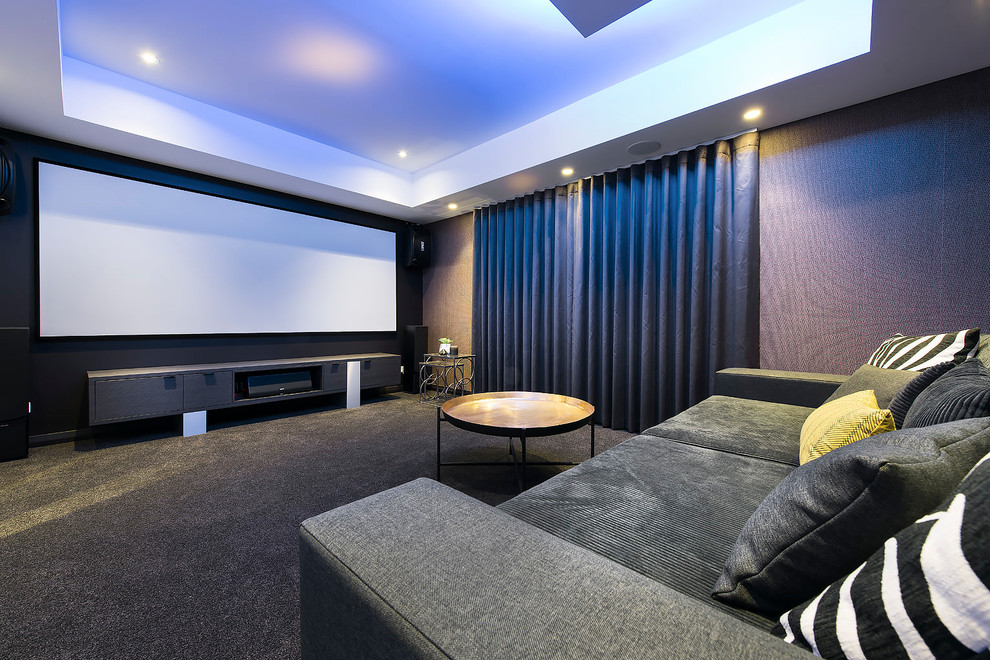 Ejemplo de cine en casa cerrado actual con paredes multicolor, moqueta, pantalla de proyección y suelo gris