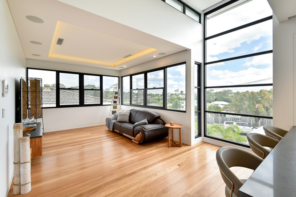 Mittelgroßes, Offenes Modernes Heimkino mit weißer Wandfarbe, TV-Wand, hellem Holzboden und braunem Boden in Brisbane