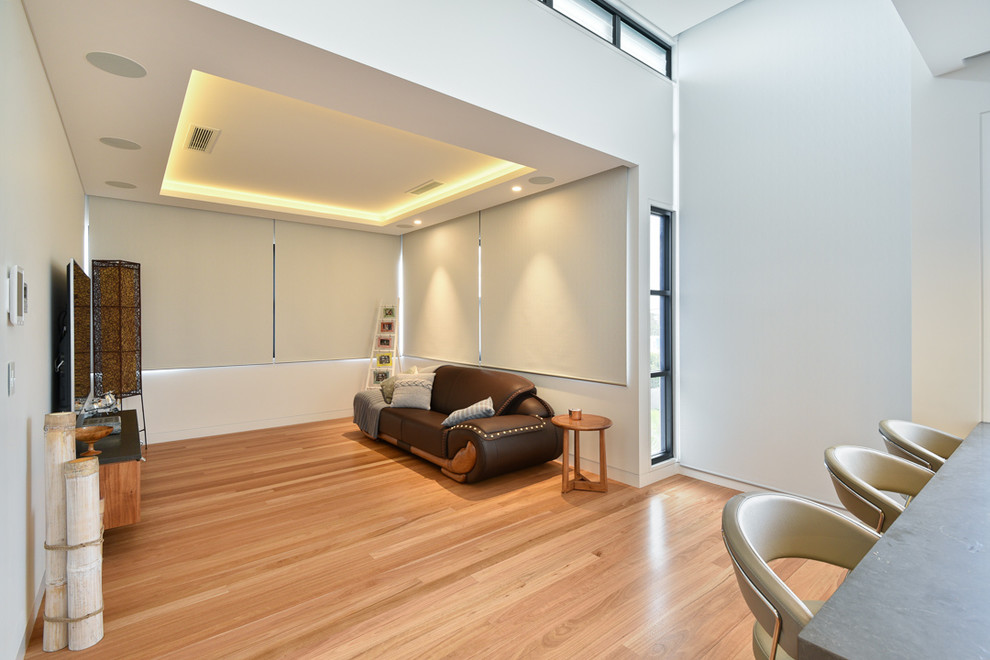 Esempio di un home theatre minimalista di medie dimensioni e aperto con pareti bianche, TV a parete, parquet chiaro e pavimento marrone