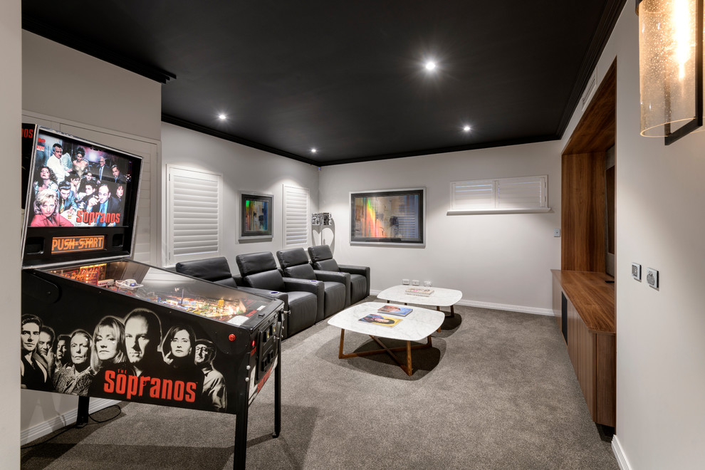 Imagen de cine en casa cerrado actual de tamaño medio con paredes grises, moqueta, pared multimedia y suelo gris