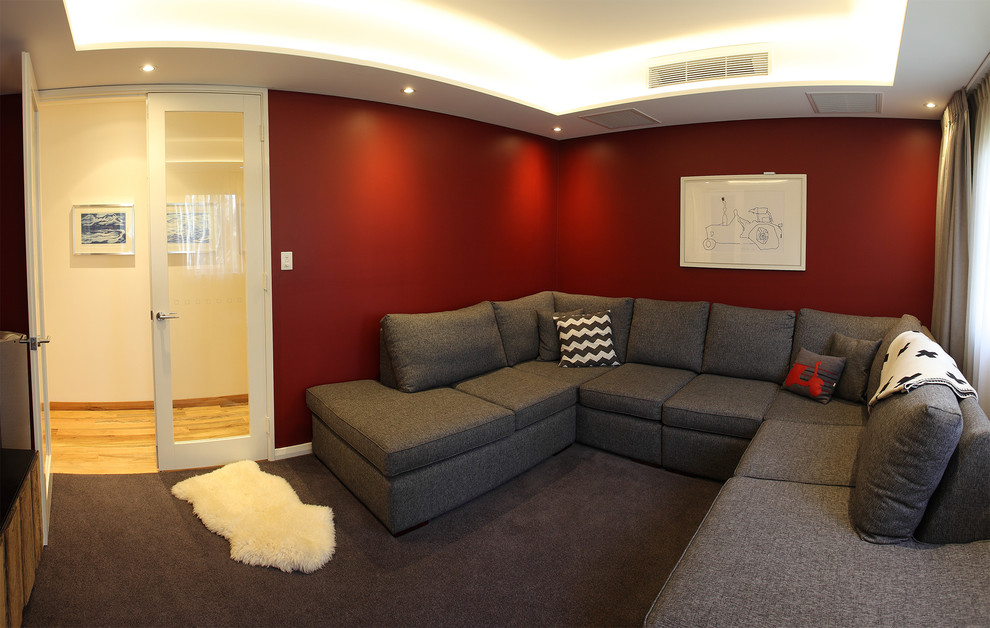 Bild på ett mellanstort funkis avskild hemmabio, med röda väggar, heltäckningsmatta och en väggmonterad TV