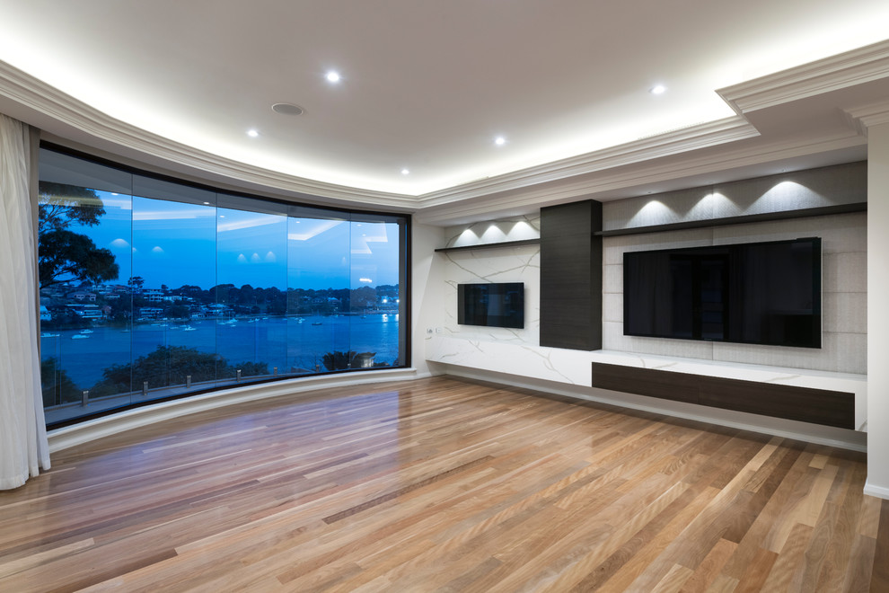 Example of a huge trendy open concept medium tone wood floor and brown floor home theater design in Perth with gray walls and a wall-mounted tv
