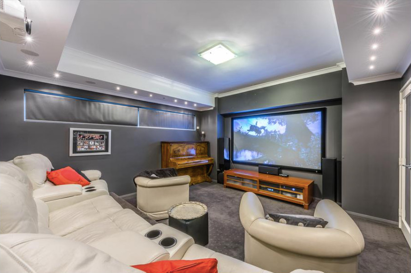 Imagen de cine en casa contemporáneo con paredes grises, moqueta y televisor colgado en la pared
