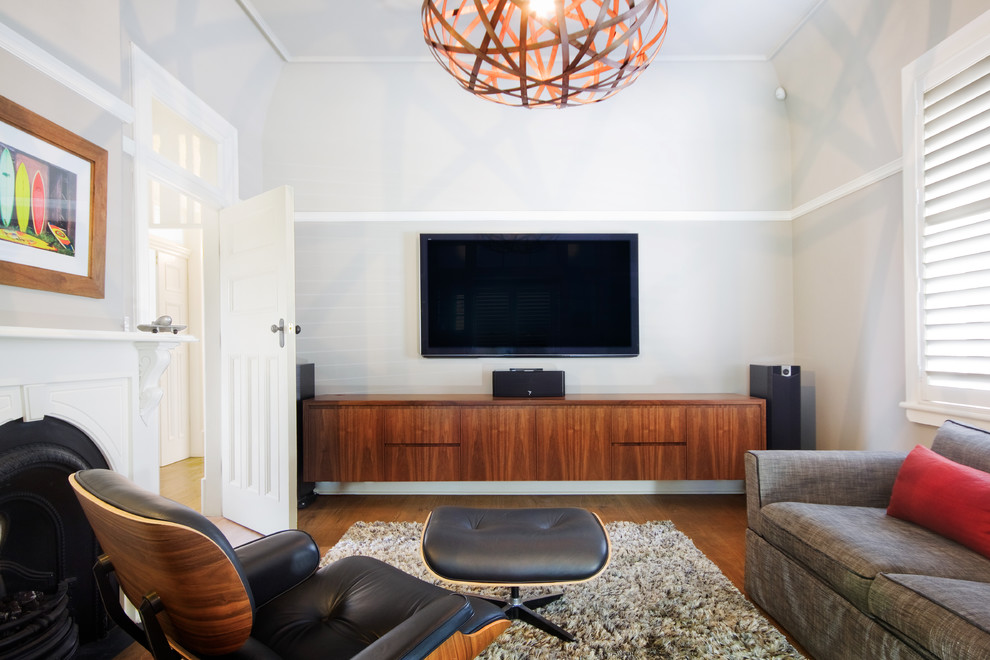 Imagen de cine en casa cerrado actual pequeño con televisor colgado en la pared, paredes beige y suelo de madera en tonos medios