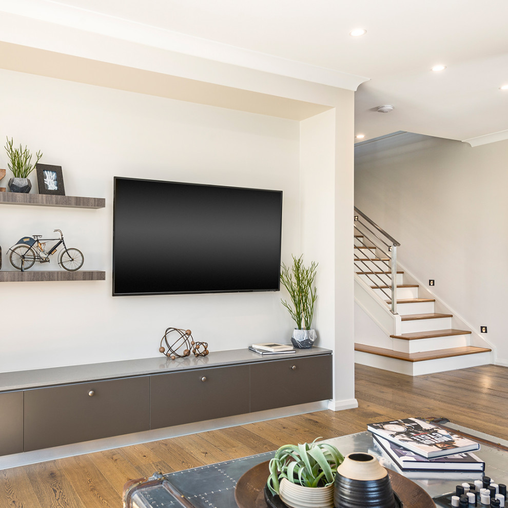 Bild på ett stort industriellt öppen hemmabio, med vita väggar, mellanmörkt trägolv, en väggmonterad TV och brunt golv