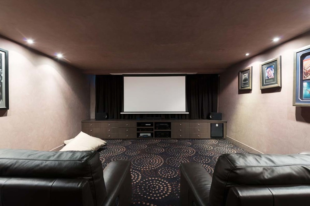 Idées déco pour une grande salle de cinéma contemporaine fermée avec un mur beige, moquette, un écran de projection et un sol multicolore.