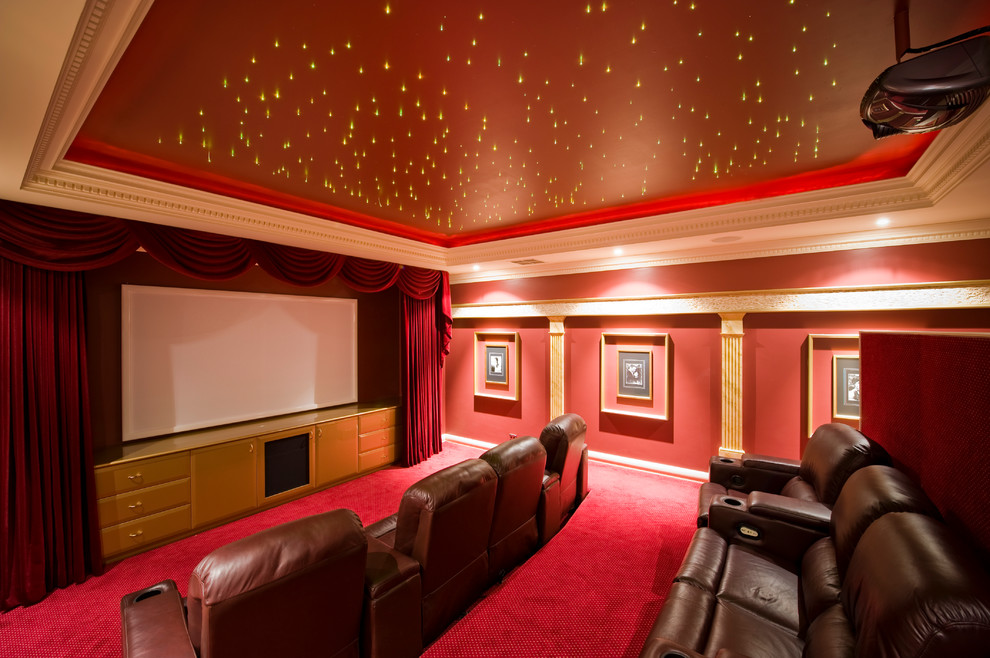 Cette photo montre une très grande salle de cinéma chic fermée avec un mur rouge, moquette, un écran de projection et un sol rouge.