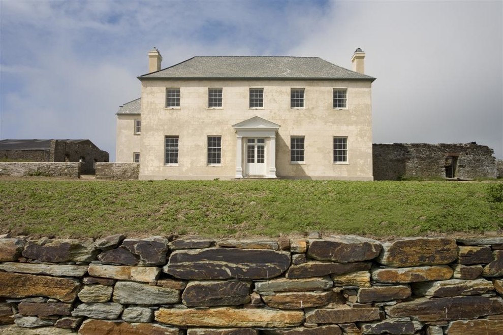 Esempio della facciata di una casa grande beige classica a due piani con rivestimento in pietra e tetto a padiglione