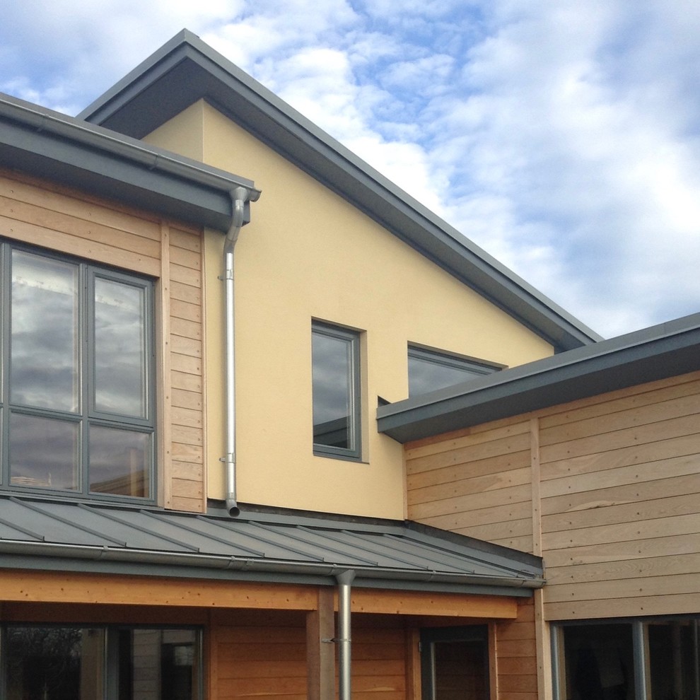 This is an example of a large and beige contemporary two floor house exterior in Other with mixed cladding and a lean-to roof.