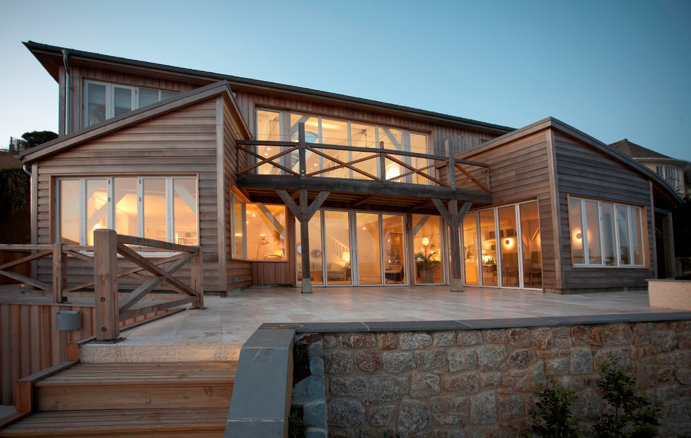 Photo of a large and brown nautical two floor house exterior in Devon with wood cladding and a lean-to roof.