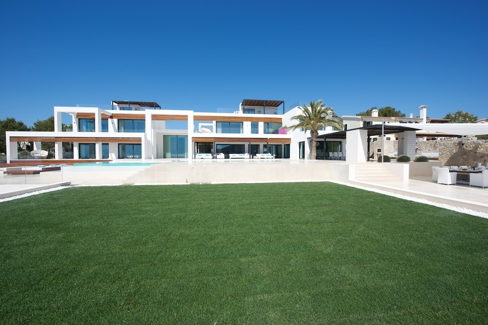 Réalisation d'une grande façade de petite villa blanche méditerranéenne à deux étages et plus avec un revêtement mixte et un toit plat.