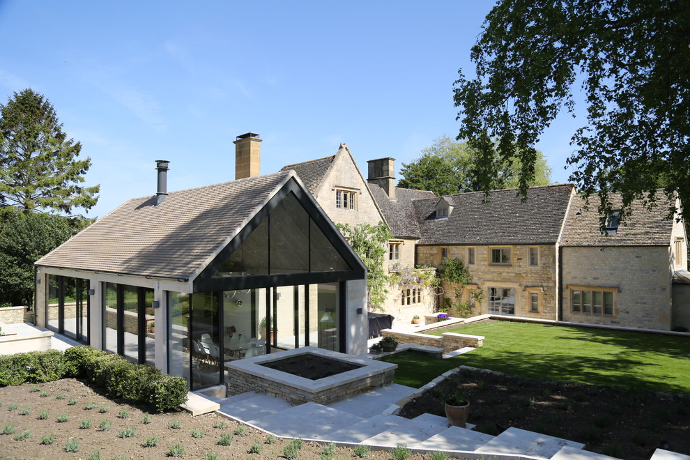 Réalisation d'une façade de maison beige champêtre en pierre de taille moyenne et à un étage avec un toit à deux pans et un toit en shingle.