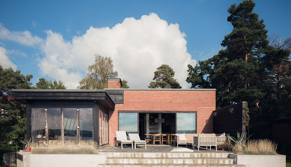 Inspiration pour une façade de maison rouge nordique en brique de taille moyenne et de plain-pied avec un toit plat.