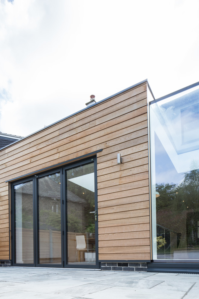 This is an example of a small contemporary bungalow semi-detached house in Other with wood cladding and a flat roof.