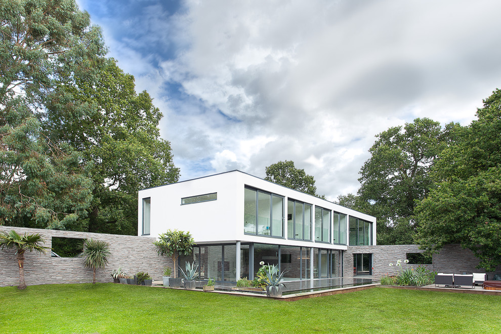 Idée de décoration pour une façade de maison blanche minimaliste de taille moyenne et à un étage avec un revêtement mixte et un toit plat.