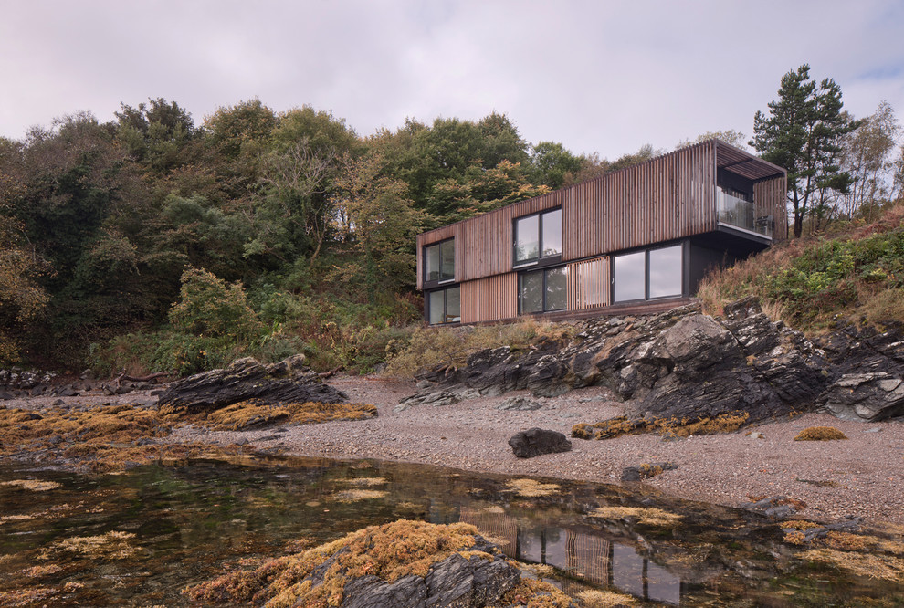 Photo of a brown beach style two floor detached house in Other with wood cladding and a flat roof.