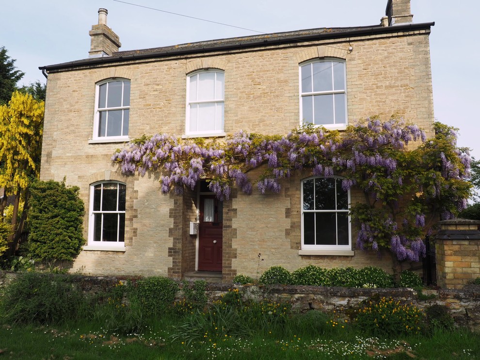 Medium sized and beige traditional two floor house exterior in Buckinghamshire with stone cladding.