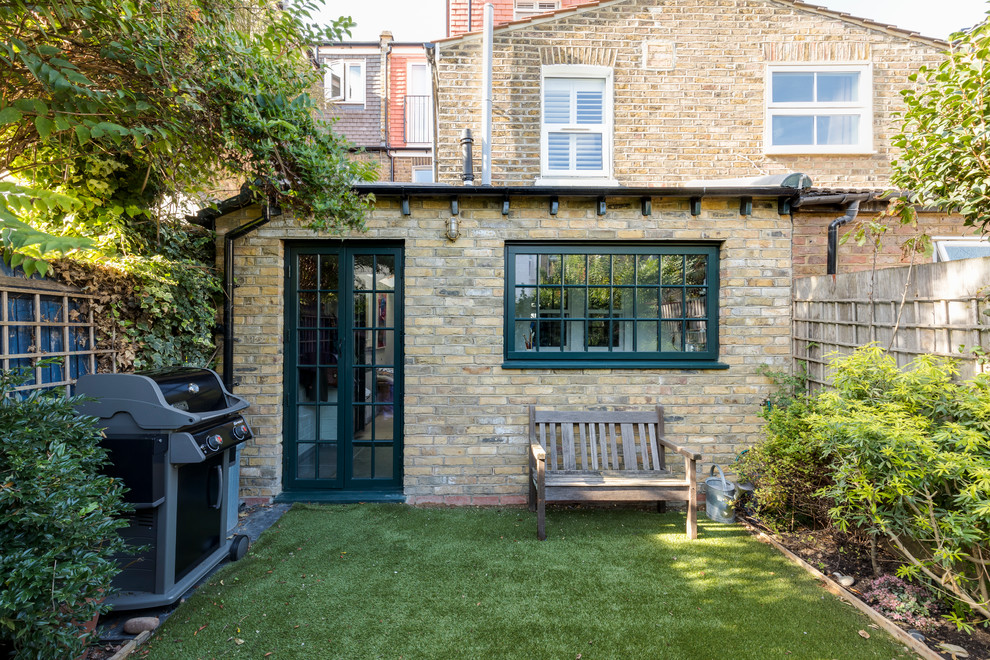 This is an example of a small and yellow industrial bungalow brick terraced house in London with a lean-to roof and a tiled roof.