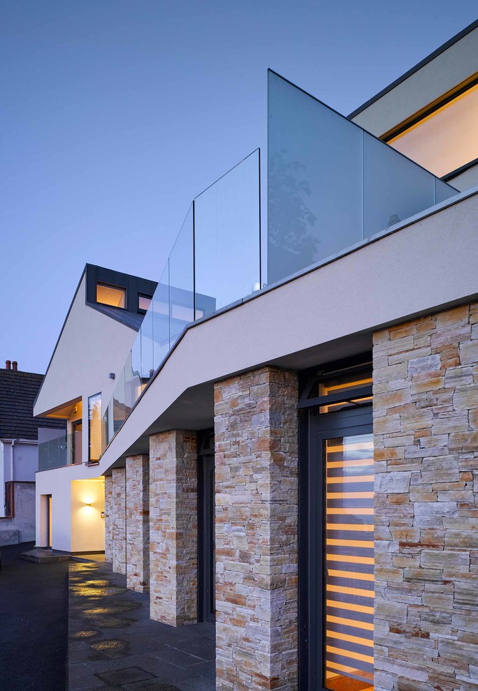 This is an example of a large and multi-coloured modern two floor render detached house in Dublin with a pitched roof and a metal roof.