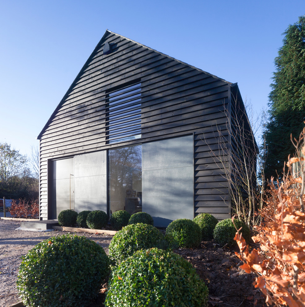 Aménagement d'une petite façade de maison noire contemporaine en bois à un étage avec un toit à deux pans.