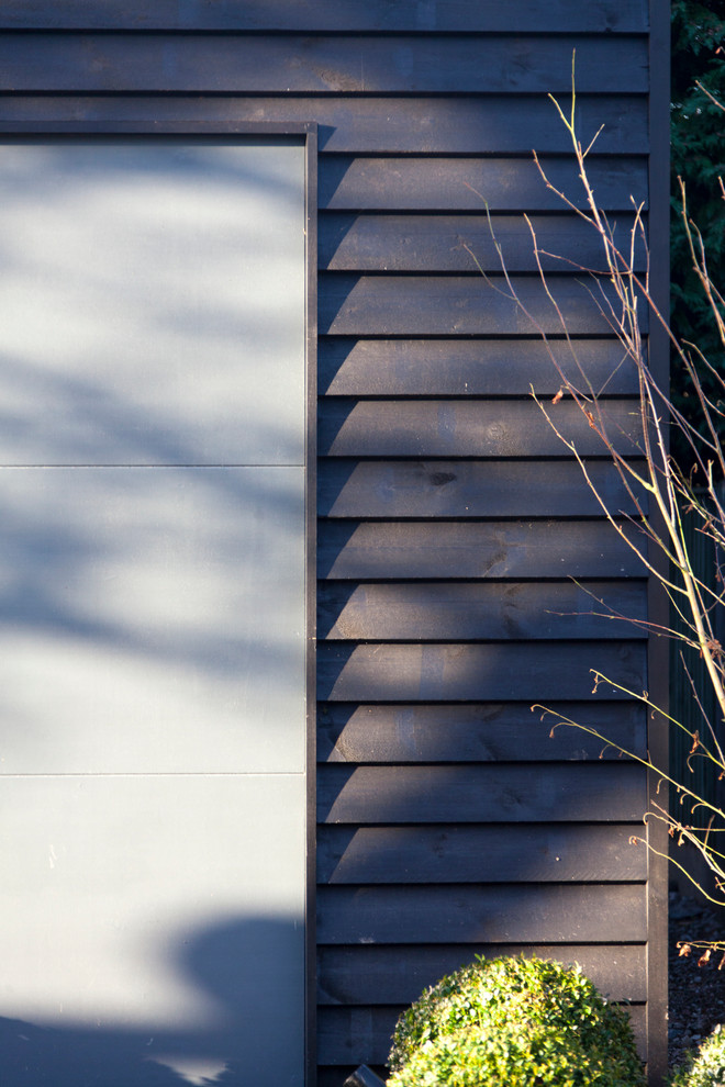 Photo of a small and black contemporary two floor house exterior in Cheshire with wood cladding and a pitched roof.