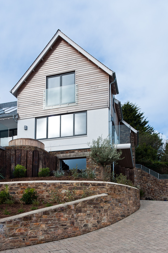Example of a beach style three-story wood exterior home design in Devon with a tile roof