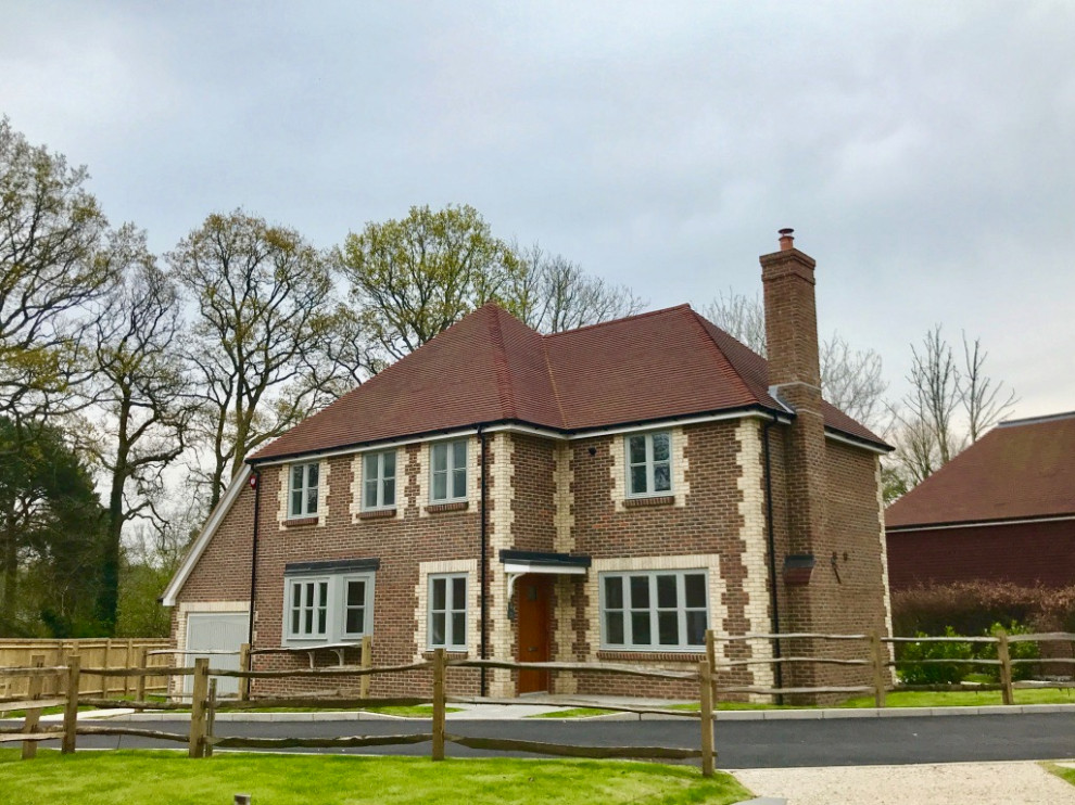 Large farmhouse beige two-story brick house exterior photo in Sussex with a clipped gable roof and a tile roof