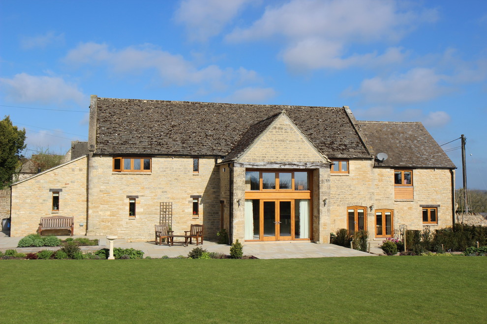 Large country multicolored two-story stone exterior home photo in Gloucestershire with a tile roof