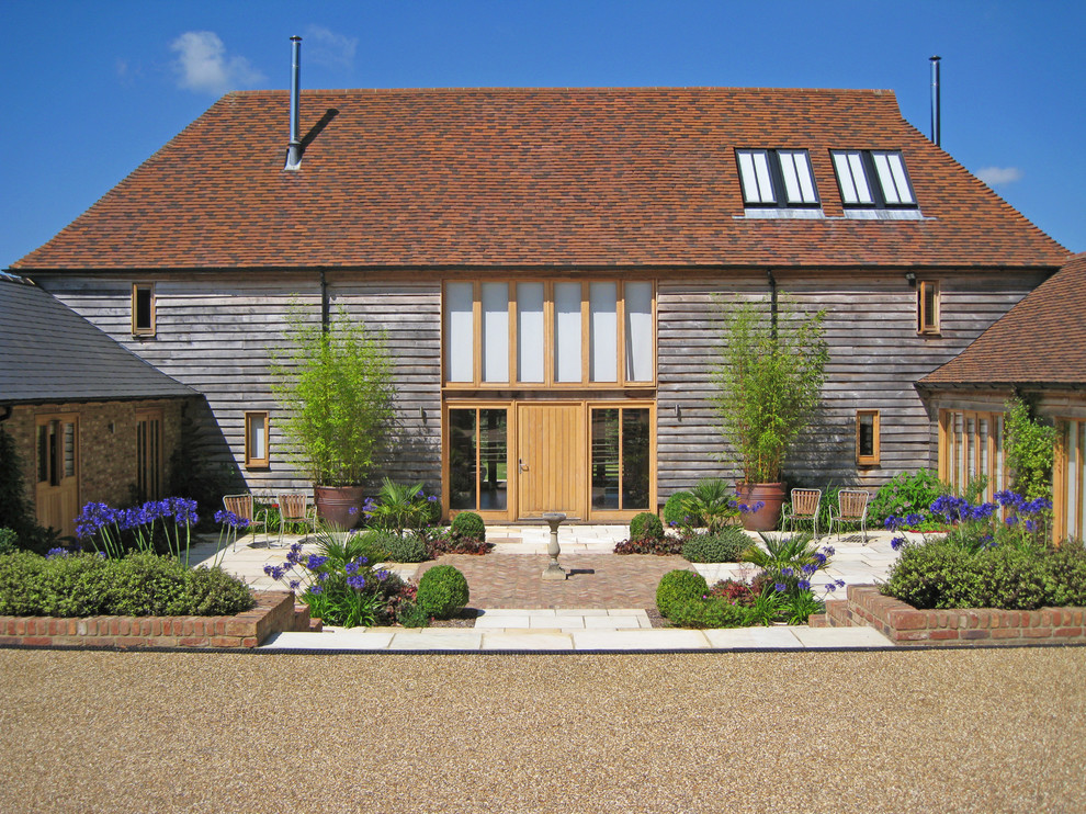 Foto della facciata di una casa country a due piani con rivestimento in legno e tetto a padiglione