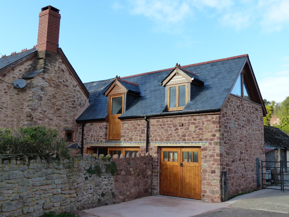 Foto della facciata di una casa marrone country a due piani con rivestimento in pietra e tetto a capanna