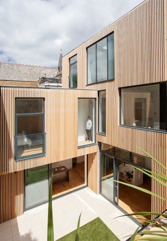 Inspiration pour une façade de maison de ville design en bois à deux étages et plus avec un toit plat.
