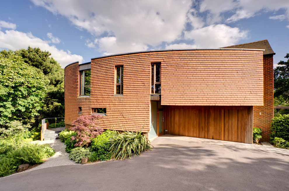 This is an example of a red contemporary two floor brick house exterior in Hampshire with a flat roof.