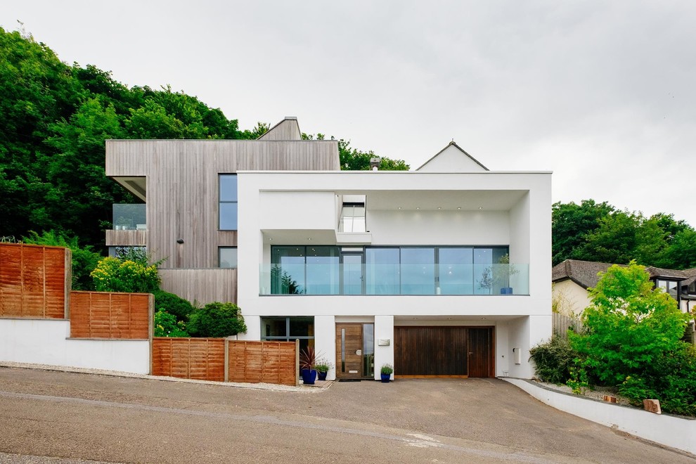 White contemporary house exterior in Cornwall with three floors, wood cladding and a flat roof.