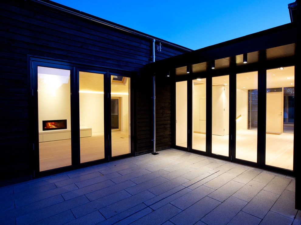 Photo of a black and medium sized contemporary bungalow house exterior in London with wood cladding.