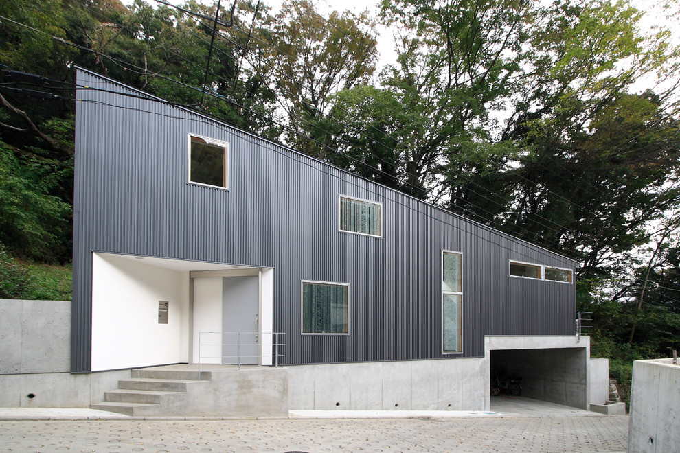 Inspiration pour une façade de maison métallique et grise design de taille moyenne et à niveaux décalés avec un toit en appentis.