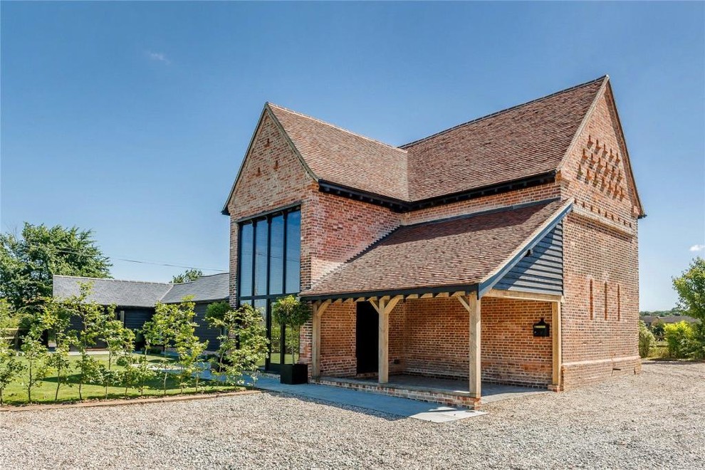 This is an example of a large and red contemporary brick detached house in Hertfordshire with three floors.