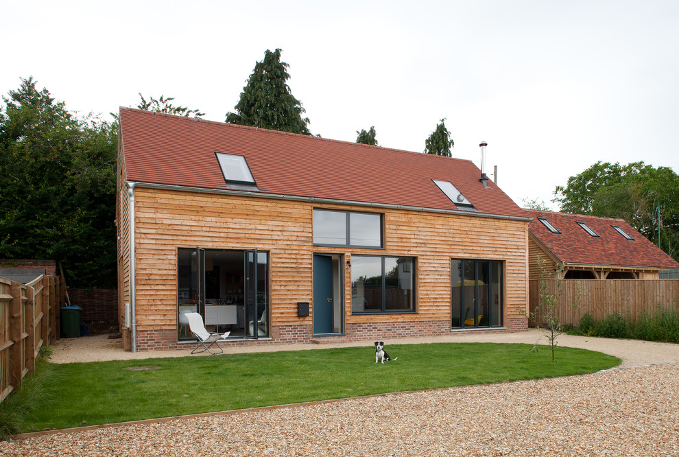 This is an example of a medium sized and beige scandi detached house in Buckinghamshire with three floors, wood cladding and a pitched roof.
