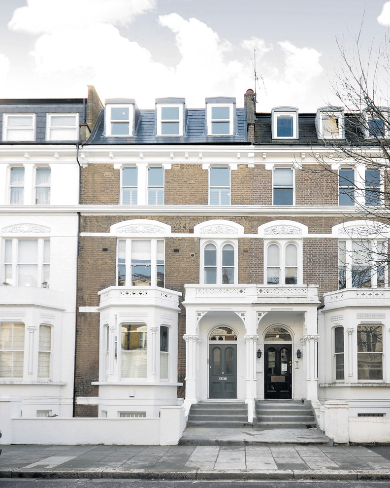 Photo of a brown traditional brick terraced house in London with three floors and a pitched roof.