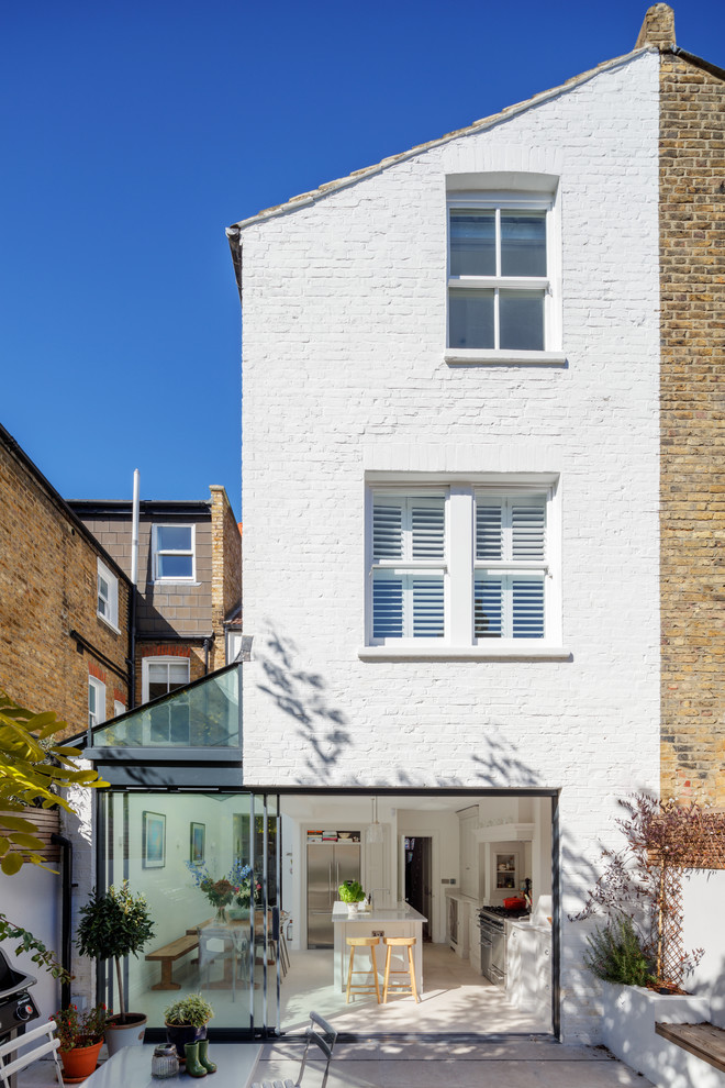 This is an example of a medium sized and white contemporary brick terraced house in London with three floors, a pitched roof and a tiled roof.