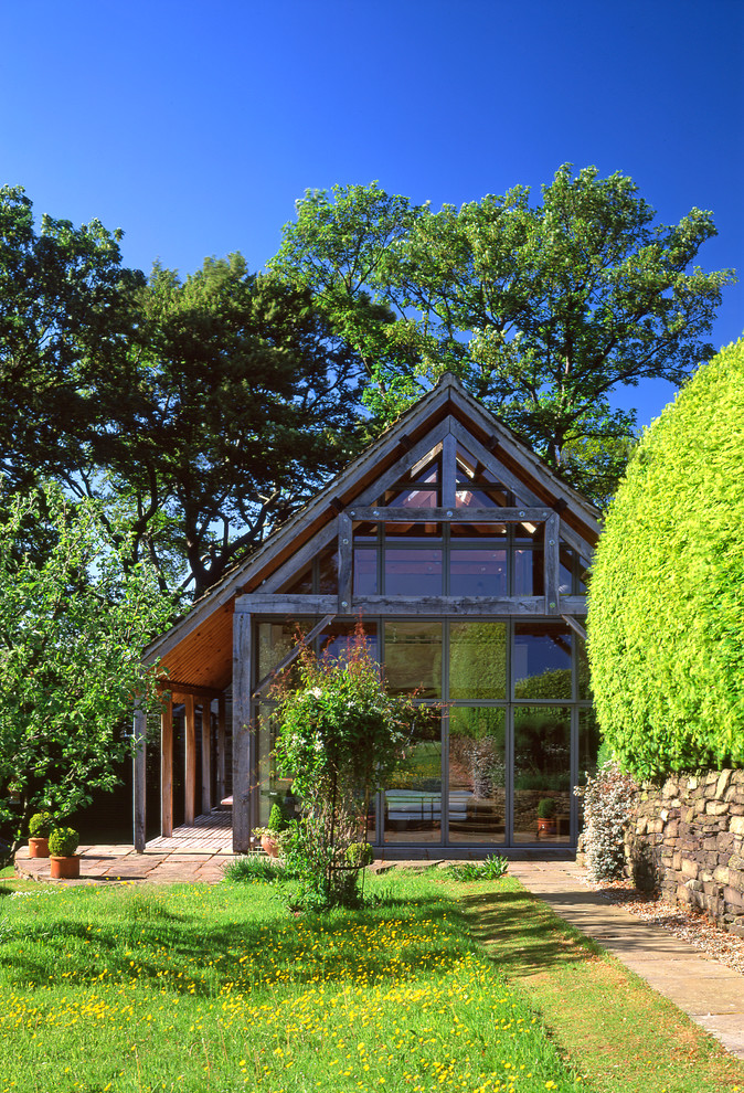 Exemple d'une façade de maison nature en verre de plain-pied avec un toit à deux pans.