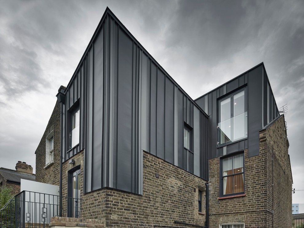 Example of a mid-sized trendy gray two-story metal exterior home design in London with a clipped gable roof