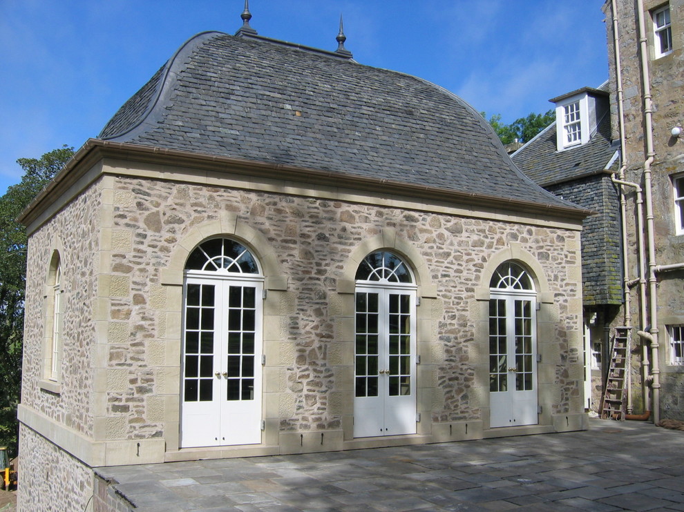 Пример оригинального дизайна: бежевый дом среднего размера в классическом стиле с облицовкой из камня и двускатной крышей