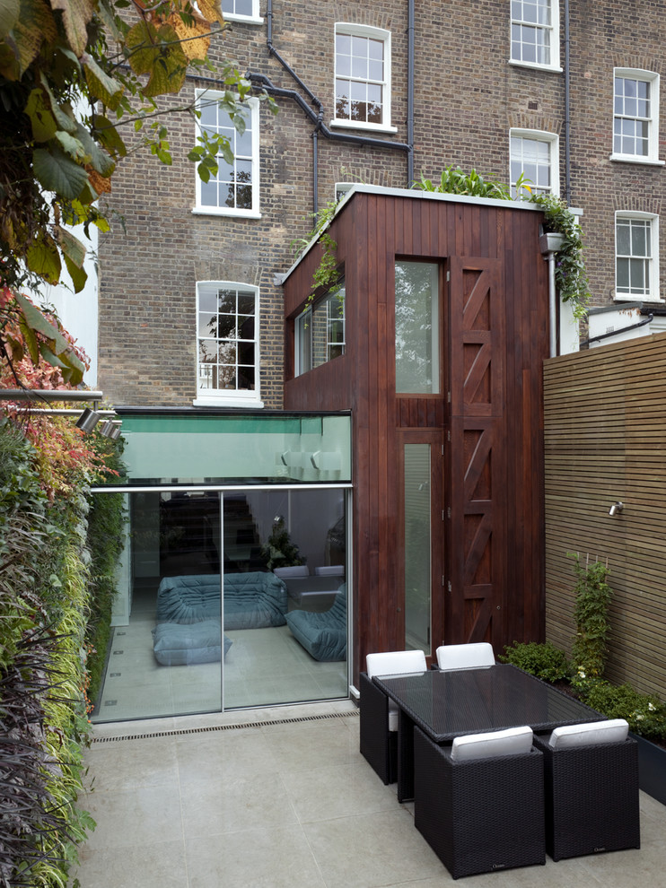 Medium sized and white contemporary house exterior in London with three floors, wood cladding and a mansard roof.