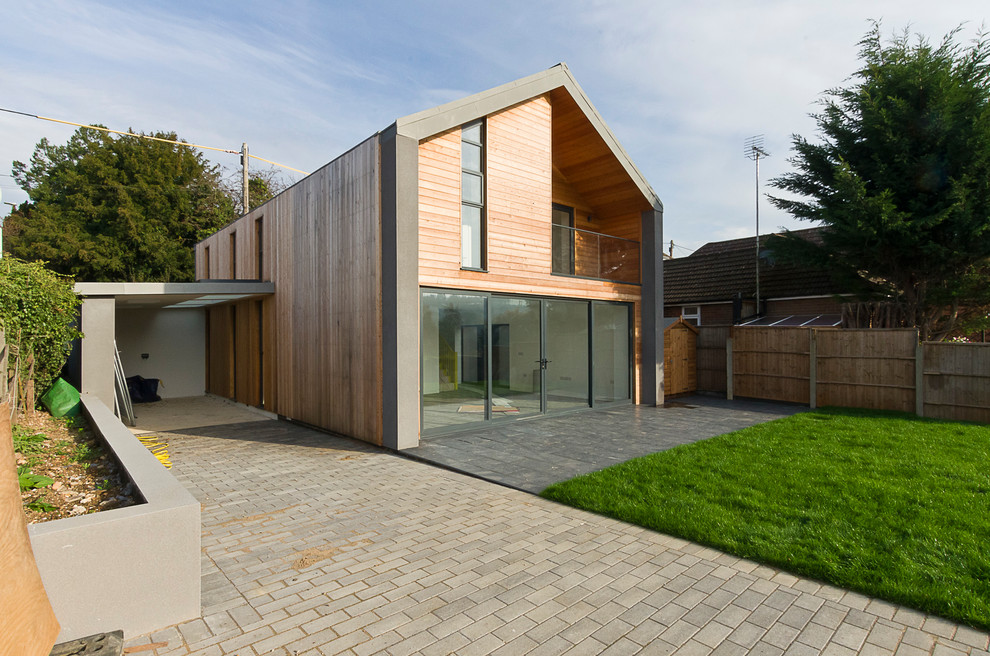 Medium sized and gey contemporary two floor detached house in Hertfordshire with wood cladding, a pitched roof and a metal roof.