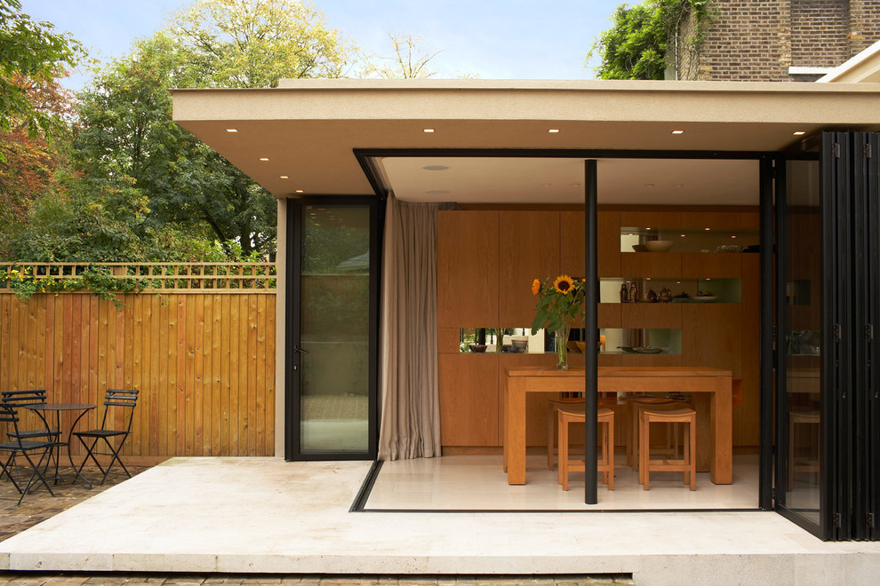 Photo of a medium sized and beige modern bungalow render house exterior in London.