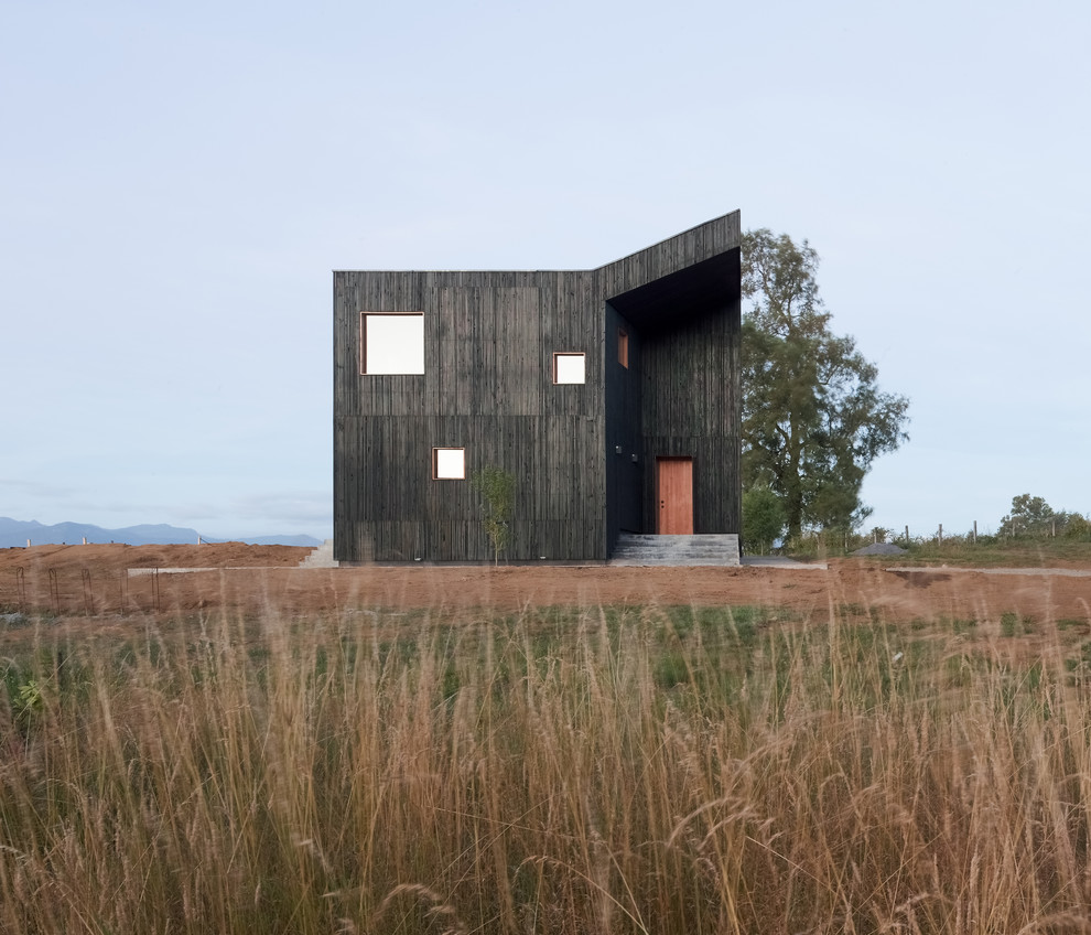 Idée de décoration pour une grande façade de maison noire minimaliste en bois à un étage avec un toit en métal et un toit plat.